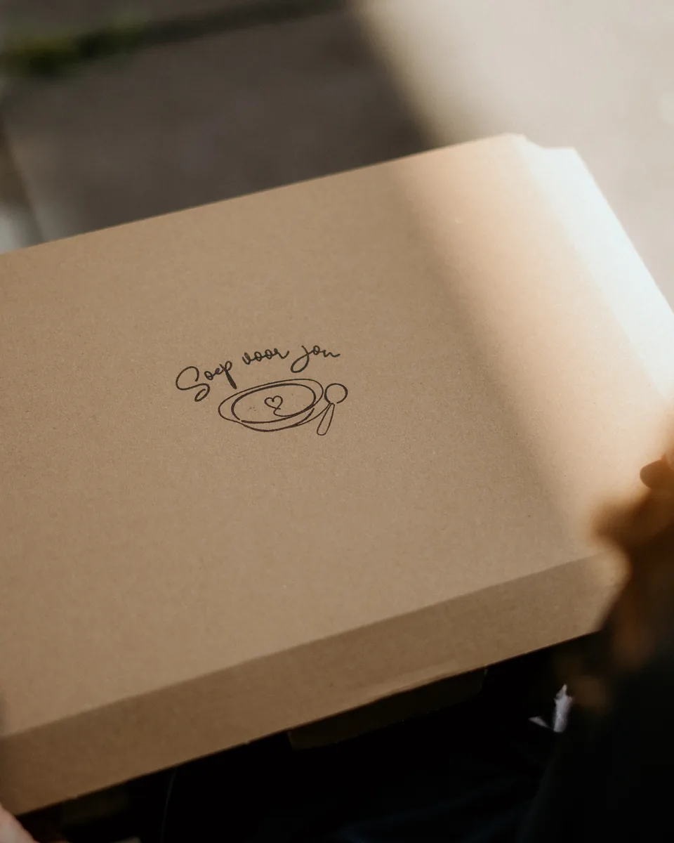 Het brievenbuspakket van Soep voor jou wordt geopend, met het logo op de doos
