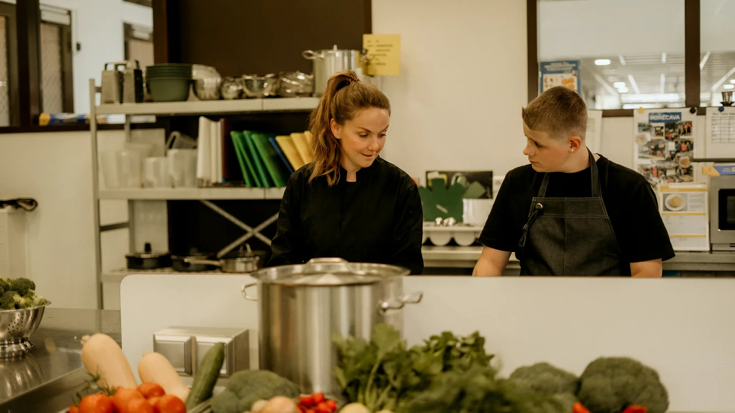 Leerlingen en koks snijden groenten in de keuken van College De Trappenberg
