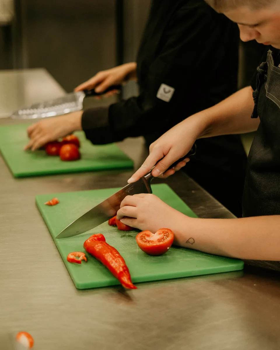 Leerlingen snijden verse groenten in de keuken van het leerbedrijf